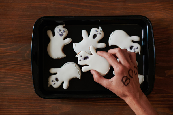 Someone Takes Halloween Cookie in Shape of Ghost from Baking Tray